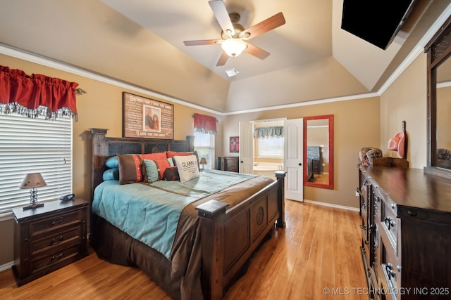 bedroom featuring lofted ceiling, ornamental molding, ceiling fan, a tray ceiling, and light wood-type flooring