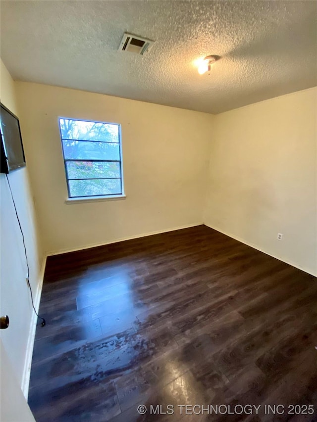 empty room with a textured ceiling and dark hardwood / wood-style flooring