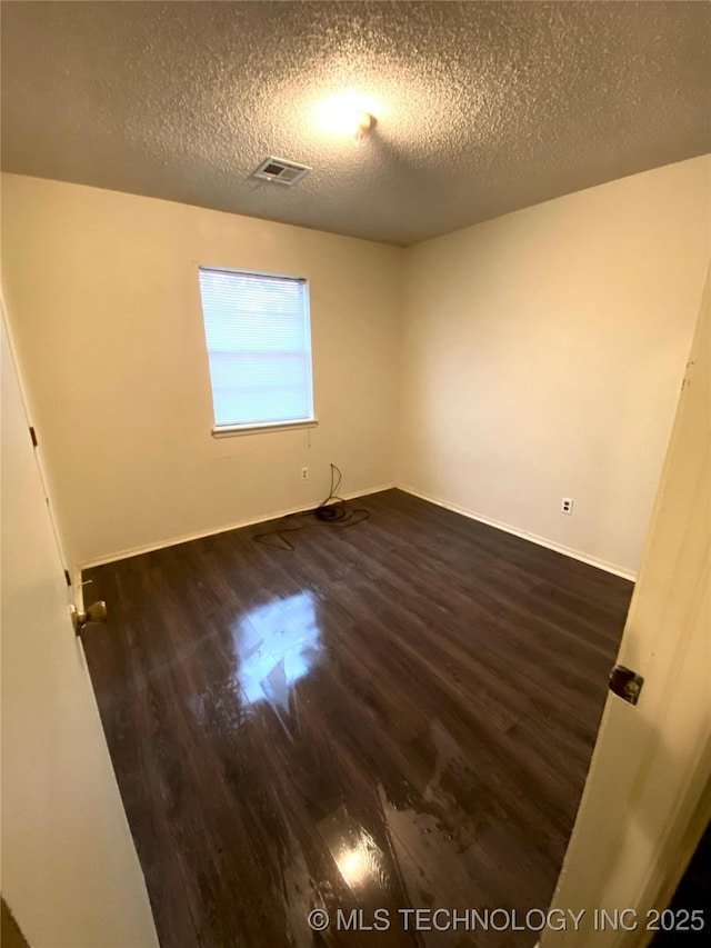 unfurnished room featuring a textured ceiling and dark wood-type flooring