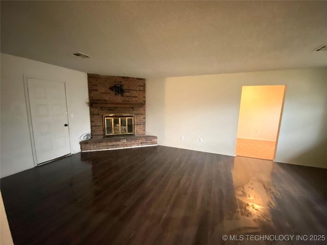 unfurnished living room with wood-type flooring, a brick fireplace, and a textured ceiling