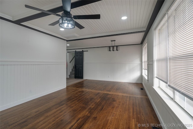 empty room featuring ceiling fan, a barn door, and dark hardwood / wood-style flooring