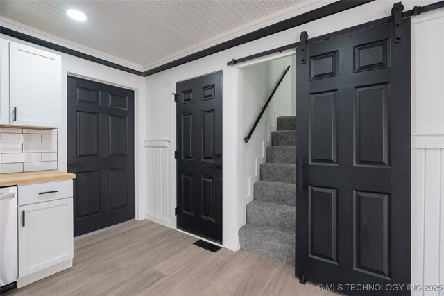 entrance foyer featuring crown molding, a barn door, and light hardwood / wood-style floors