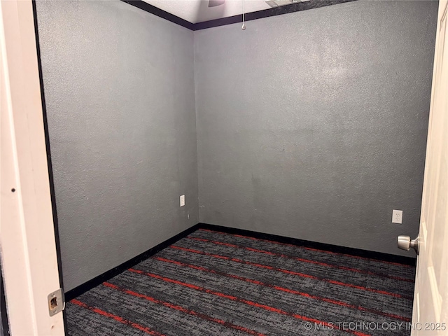 empty room with dark colored carpet and ceiling fan