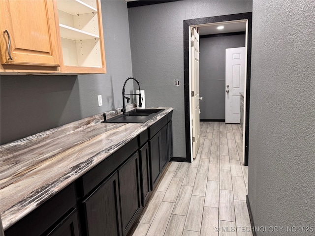 kitchen with light hardwood / wood-style floors, sink, and light stone countertops