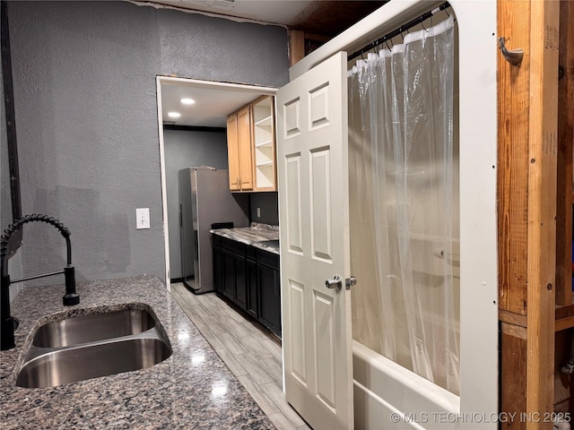 kitchen with sink, stainless steel fridge, and dark stone countertops