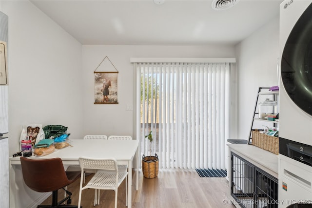 dining room with stacked washer and dryer and light hardwood / wood-style floors