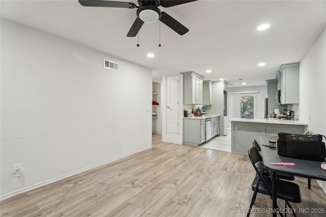 interior space with ceiling fan, gray cabinets, light hardwood / wood-style floors, stainless steel dishwasher, and kitchen peninsula