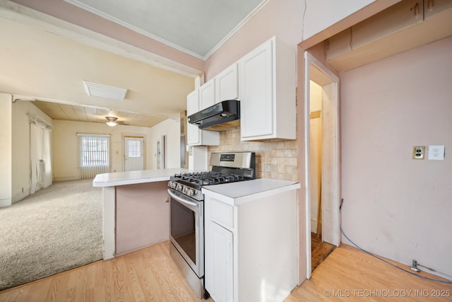 kitchen featuring white cabinets, gas stove, light hardwood / wood-style floors, backsplash, and kitchen peninsula