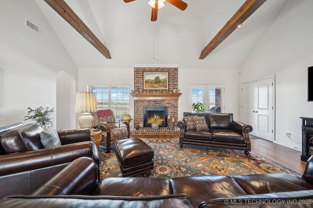 living room featuring ceiling fan, a fireplace, high vaulted ceiling, and beamed ceiling