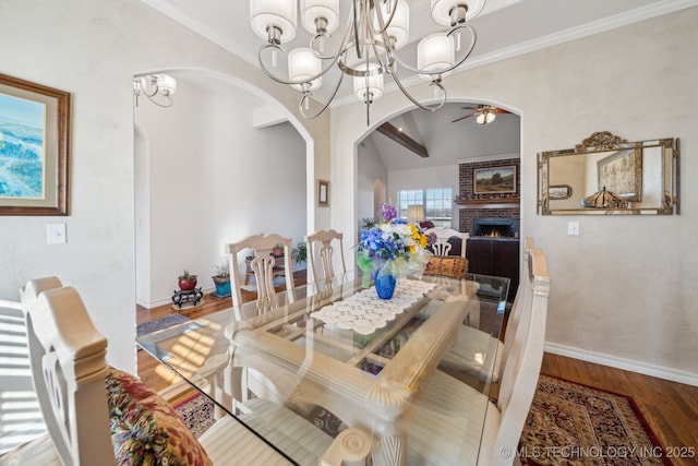 dining room with a brick fireplace, ornamental molding, ceiling fan with notable chandelier, and hardwood / wood-style flooring