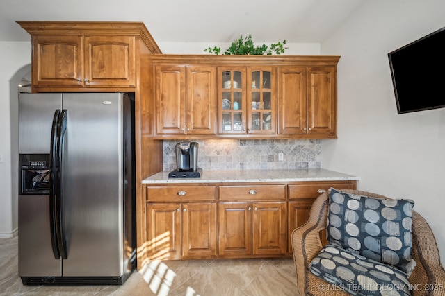 kitchen with tasteful backsplash, stainless steel fridge with ice dispenser, and light stone counters