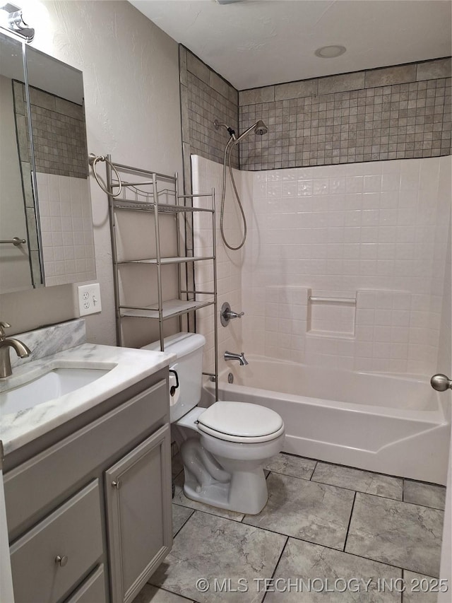 full bathroom featuring tiled shower / bath, vanity, and toilet