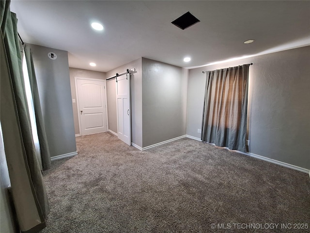 spare room with a barn door and carpet