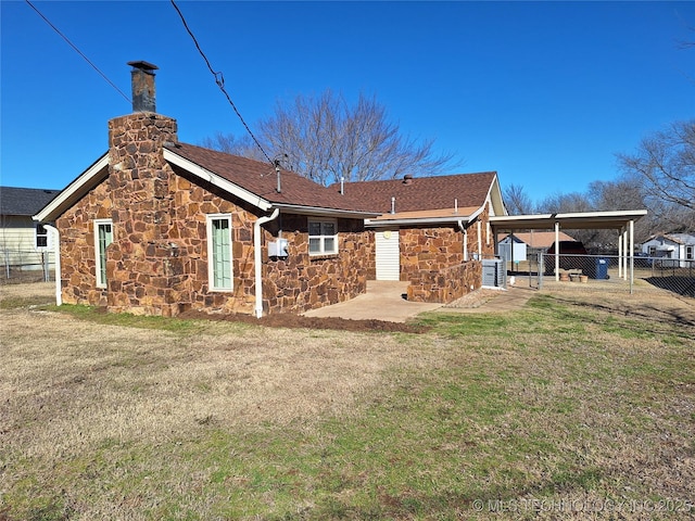 back of property with a carport and a yard