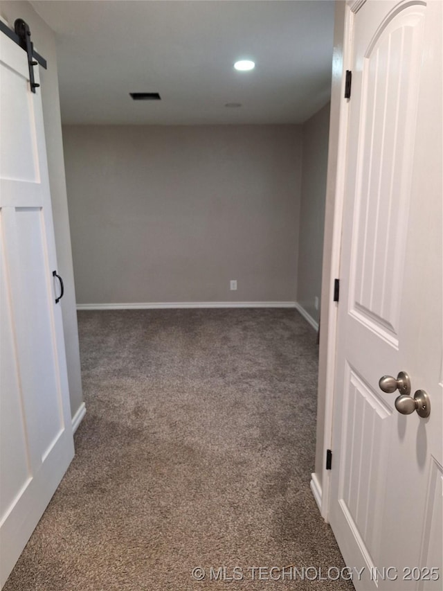 carpeted empty room featuring a barn door