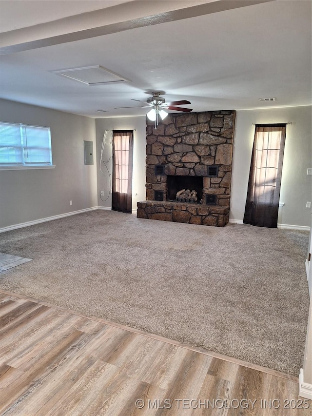 unfurnished living room featuring a fireplace, electric panel, and plenty of natural light