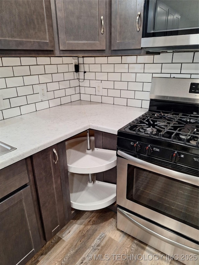 kitchen featuring tasteful backsplash, dark brown cabinetry, stainless steel appliances, and hardwood / wood-style floors