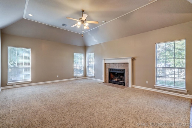 unfurnished living room with ceiling fan, lofted ceiling, a fireplace, and plenty of natural light