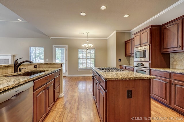 kitchen featuring pendant lighting, appliances with stainless steel finishes, a kitchen island, sink, and a notable chandelier