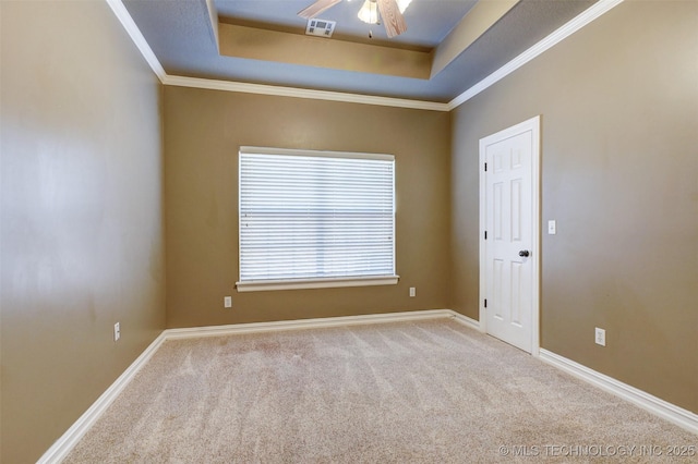 spare room featuring light carpet, a tray ceiling, and ornamental molding