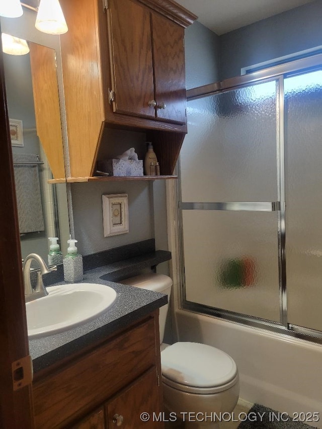 full bathroom featuring toilet, vanity, and shower / bath combination with glass door