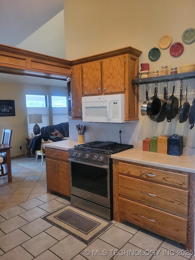 kitchen featuring light tile patterned floors, stainless steel gas range, and a towering ceiling