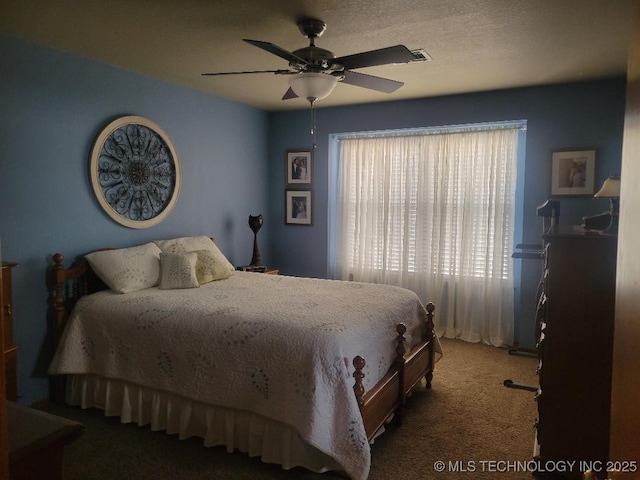 bedroom featuring ceiling fan, a textured ceiling, and dark colored carpet