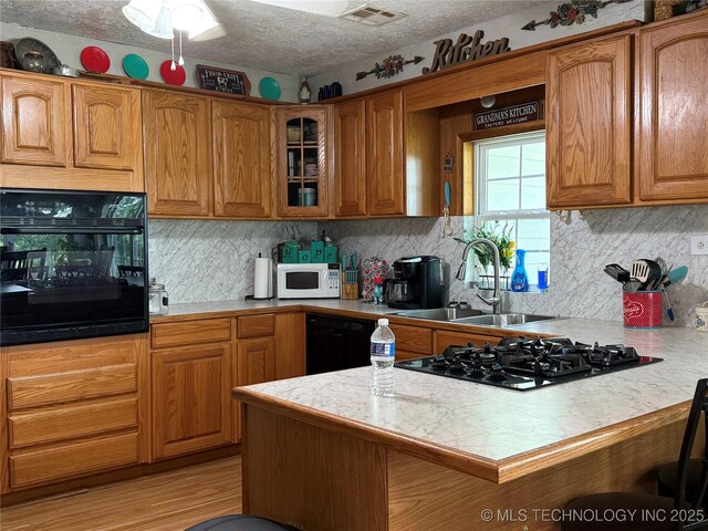5804 Samuel Rd, Kingston, OK 73439 - kitchen with black appliances, light countertops, a sink, glass insert cabinets, and a peninsula