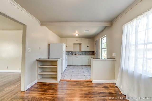 kitchen with hardwood / wood-style floors, white cabinetry, white refrigerator, backsplash, and kitchen peninsula