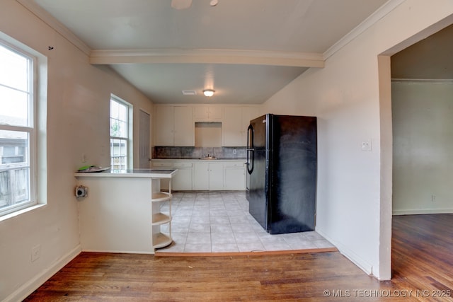 kitchen featuring white cabinets, kitchen peninsula, light hardwood / wood-style flooring, and black fridge