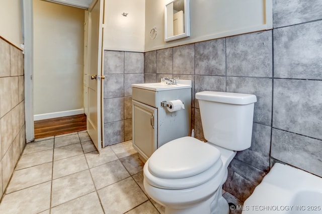 bathroom with toilet, tile patterned flooring, tile walls, and vanity