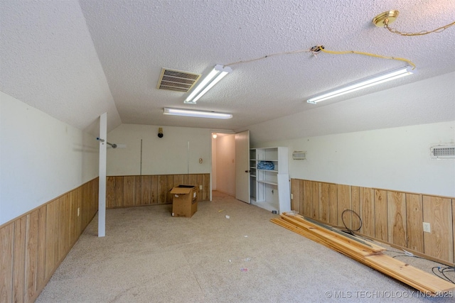 interior space featuring lofted ceiling, light carpet, and a textured ceiling