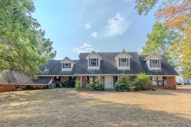 new england style home featuring central air condition unit, brick siding, and a front yard