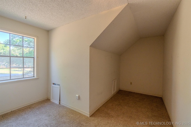 bonus room featuring a textured ceiling, baseboards, light colored carpet, and vaulted ceiling