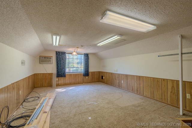 bonus room with an AC wall unit, light colored carpet, a textured ceiling, and vaulted ceiling