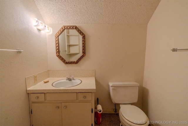 half bath with a textured ceiling, vanity, and toilet