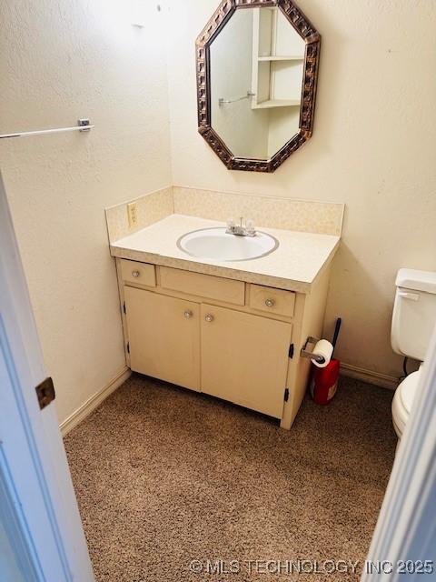 half bathroom with toilet, vanity, and baseboards