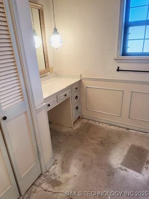 bathroom featuring a decorative wall, wainscoting, vanity, and concrete flooring