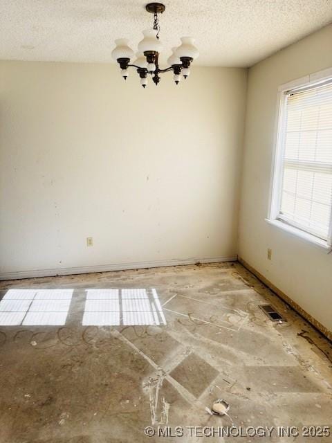 unfurnished room with a textured ceiling and a chandelier