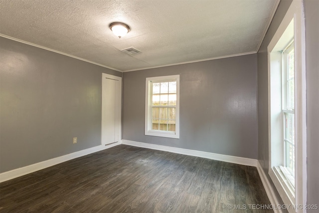 empty room featuring a textured ceiling, dark wood-type flooring, ornamental molding, and a healthy amount of sunlight