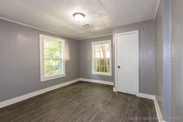 empty room featuring a textured ceiling, dark hardwood / wood-style floors, and ornamental molding