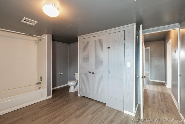 interior space featuring hardwood / wood-style flooring, toilet, and bathing tub / shower combination