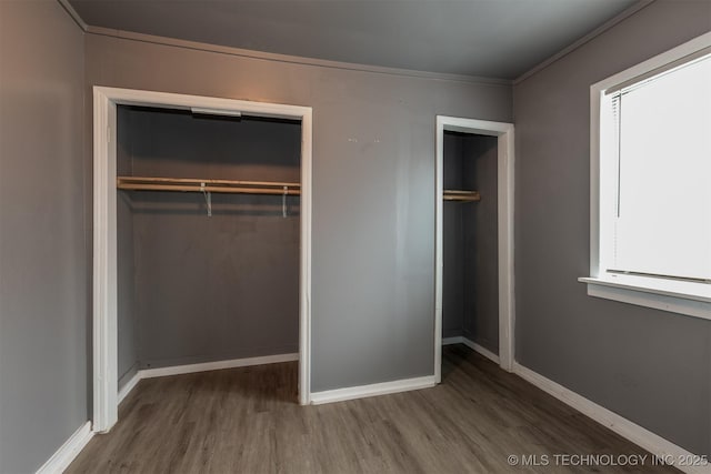 unfurnished bedroom with wood-type flooring, a closet, and crown molding