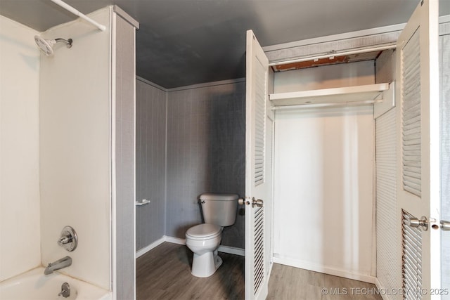 bathroom with toilet, shower / bath combination, and wood-type flooring