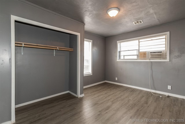 unfurnished bedroom with a closet, multiple windows, and hardwood / wood-style flooring