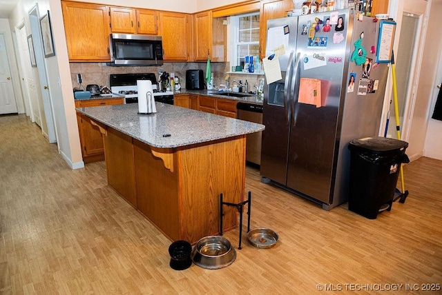 1799 W Main St, Westville, OK 74965 - kitchen featuring appliances with stainless steel finishes, brown cabinets, light wood finished floors, decorative backsplash, and a sink