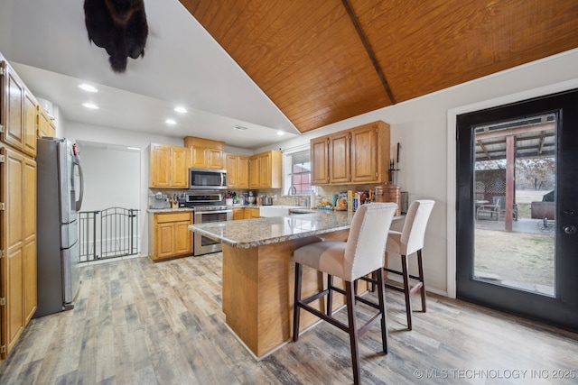 kitchen with kitchen peninsula, wooden ceiling, stainless steel appliances, a breakfast bar area, and light hardwood / wood-style flooring