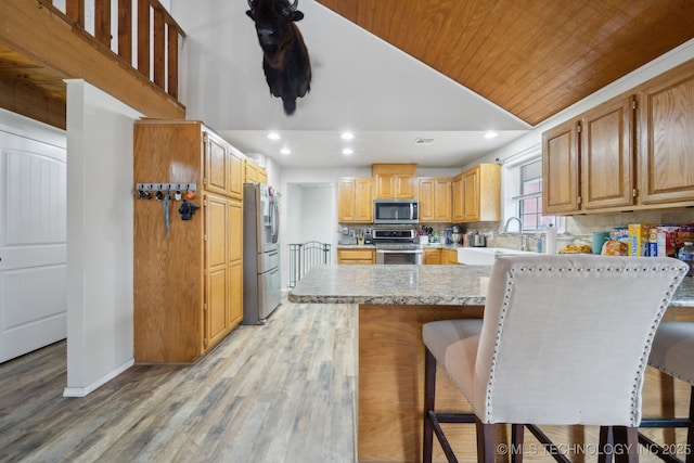 kitchen with a kitchen bar, sink, appliances with stainless steel finishes, and wood ceiling