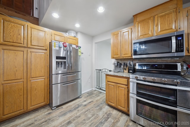 kitchen featuring tasteful backsplash, appliances with stainless steel finishes, and light hardwood / wood-style flooring