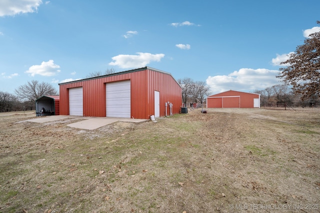 view of outdoor structure with a garage, a carport, and a yard